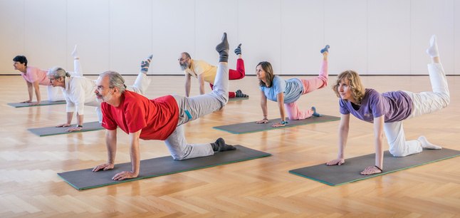 A Yoga in Daily Life class practising a posture on mats